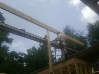Carpenter setting a ridge beam over a new addition frame — Ice Dam Removal by Roofing Brothers in Provincetown