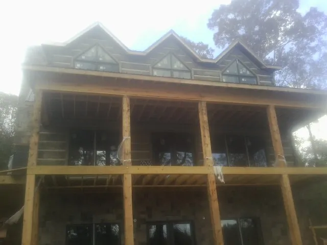 Dormers and porch framing on a large log home under construction — Roof Coating work by our crew in Provincetown