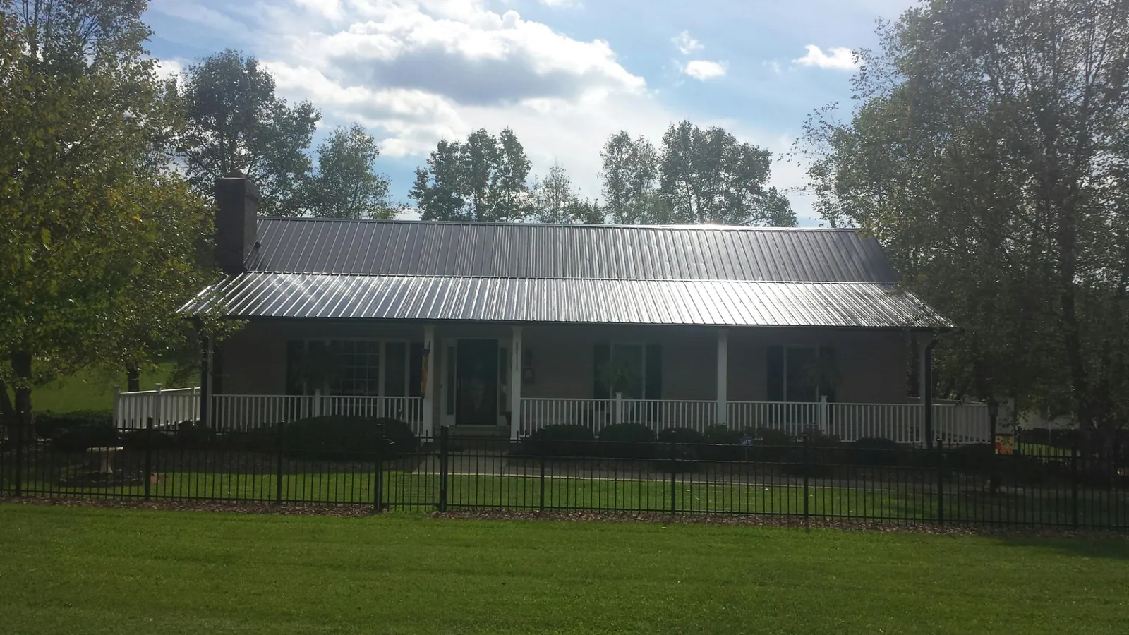 Gray metal roof on a brick ranch with a full width front porch — Gutter Guard Installation work by our crew in Provincetown