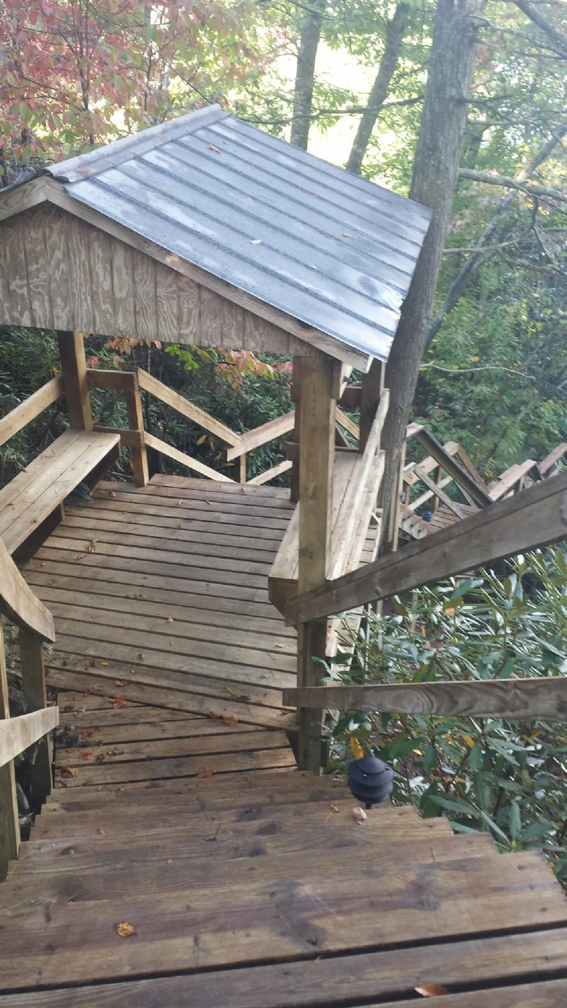 Metal roofed shelter over wooden steps on a wooded walkway — Skylight Repair & Installation work by our crew in Provincetown