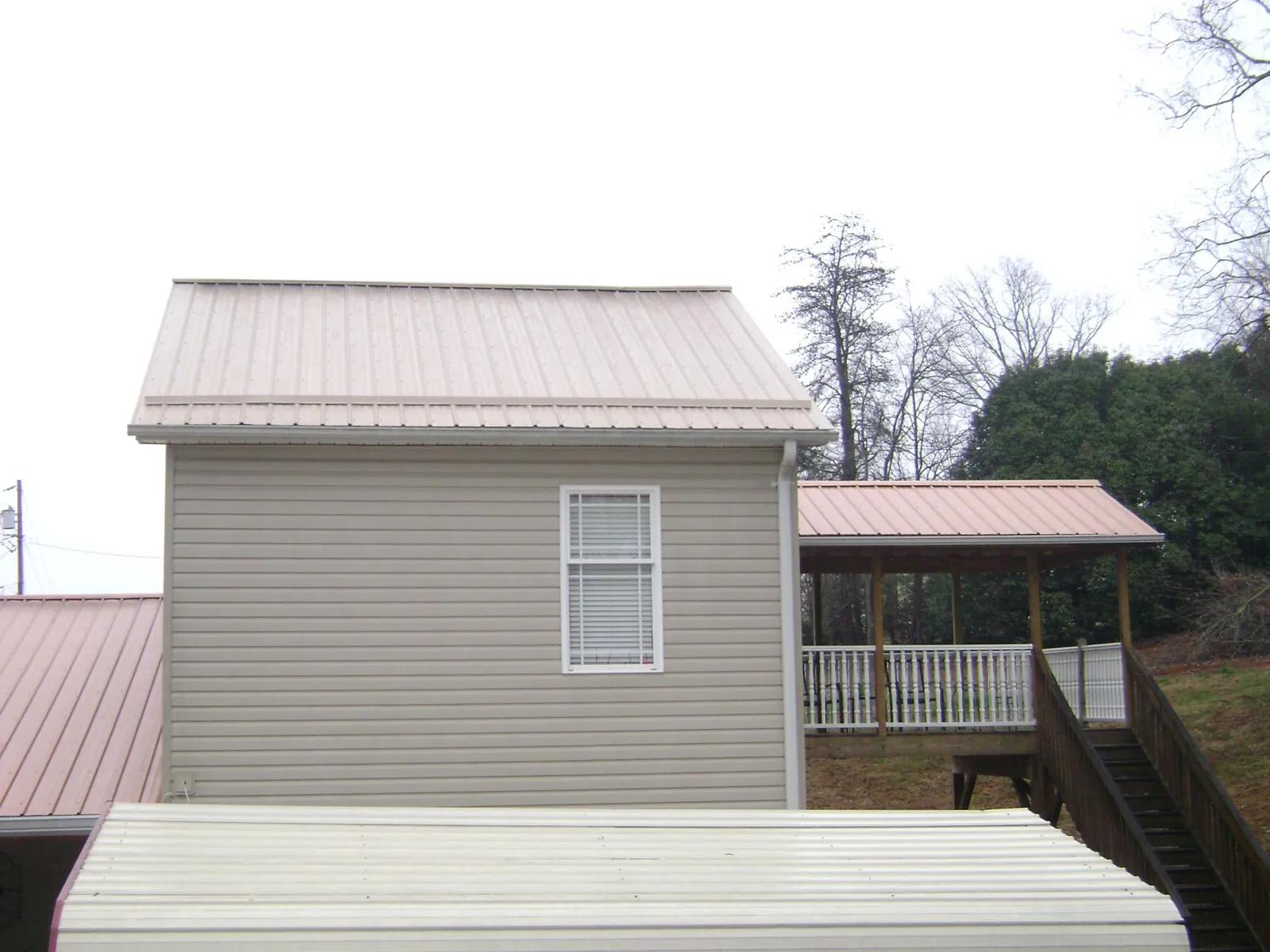 Tan metal roofs on a two story addition and attached porch, from a Roof Replacement job in Provincetown