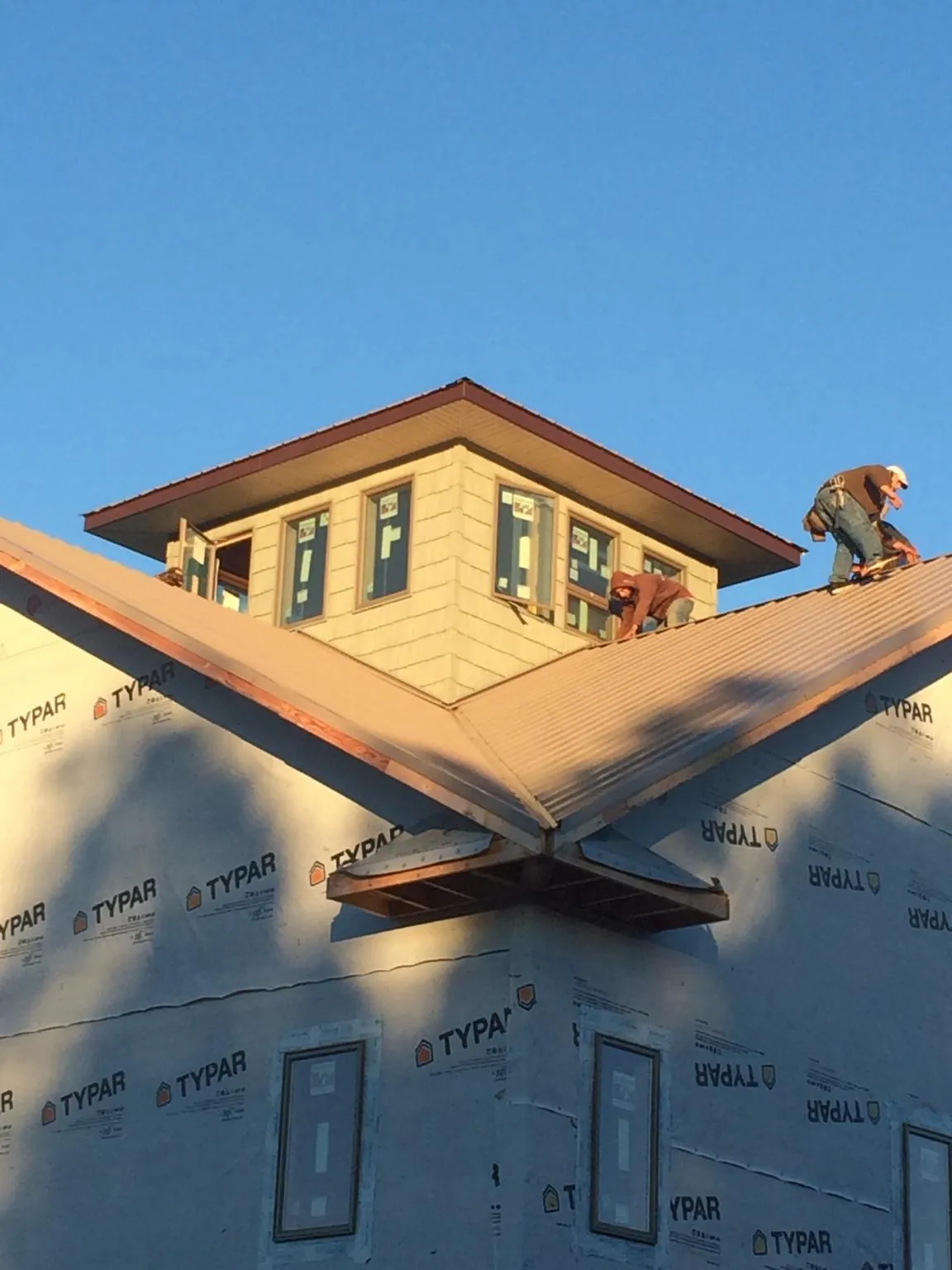 Roofers working around a rooftop cupola on a new metal roof at sunset — Roof Waterproofing in Provincetown by Roofing Brothers